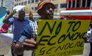 A protester holds a sign during a demonstration by opposition parties against the introduction of bond notes as a currency in Harare, Zimbabwe 30 November 2016