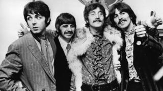 The Beatles in different kinds of clothes looking happy