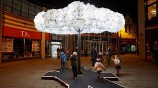 children-pull-chains-and-play-beneath-a-light-up-tree.