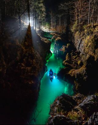 Image shows canoeist in water in dark