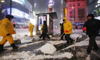 A crew of snow shovellers work as a snowstorm sweeps through Times Square on 14 March, 2017, in New York.