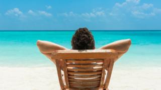 Hombre acostado en silla de extensión en la playa