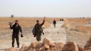 Syrian soldiers gesture as they walk down a road near Kweyris military airport, in Aleppo province (18 October 2015)