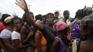 People queue for food and clothes being distributed at a shelter in Port-Salut, southwest of Port-au-Prince, on 9 October