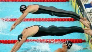 Swimmers jump into the pool
