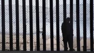 A man is seen standing on the Mexico side of a border fence separating the US at Border Field State Park in San Diego, California.