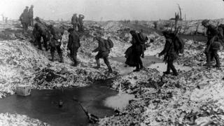 British soldiers crossing a shell-cratered, cold landscape along the River Somme