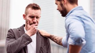 Una persona poniéndole la mano en el hombro a otra