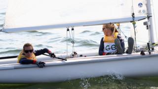 Hannah Mills and Saskia Clark wait to compete as light wind delays the start of the women's 470 race
