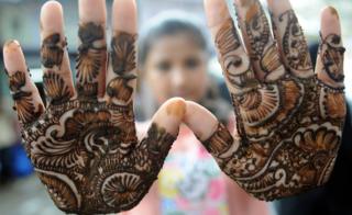 An Indian Muslim girl displays her henna decorated hands at a roadside stall ahead of the Muslim festivities of Eid al-Fitr, in Mumbai on July 28, 2014