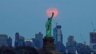 The last supermoon of 2019 'Super Worm Equinox Moon' rises behind the Statue of Liberty in New York