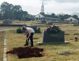 A man rakes soil over a grave in the Lee family cemetery plot, Saturday, 20 February, 2016, in Monroeville, Alabama.