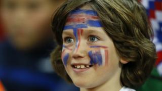 A girl with her face painted with the French flag looks on ahead of the international friendly soccer match between England and France