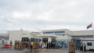 Private security guards stand guard at the main gate of the Maruti Suzuki Production Facility in Manesar