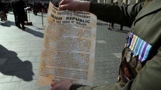 An Irish soldier holds the a copy of the 1916 Proclamation of the Irish Republic outside the General Post Office (GPO), the scene of the 1916 Easter Rising, in Dublin on March 27, 2016 as part of a programme of commemorative events to mark the 100th anniversary of the Easter Rising