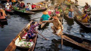 Image shows people and boats on a river