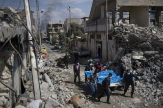 Residents carry the bodies of several people killed during fights between Iraqi security forces and Islamic State on the western side of Mosul, Iraq, on 24 March, 2017.