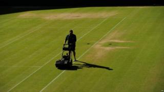 A man mows the grass on a court