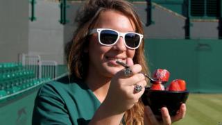 A member of ground staff at Wimbledon eats strawberries