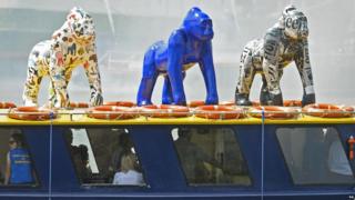 Three colourful, life-size gorilla sculptures on top of a boat in Bristol.
