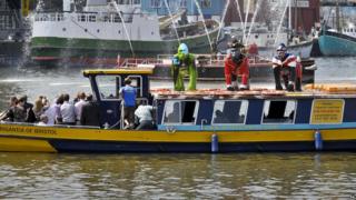 Three colourful, life-size gorilla sculptures on top of a boat in Bristol.