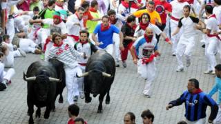 People running with the bulls during the sixth San Fermin Festival bull run in Pamplona, Spain