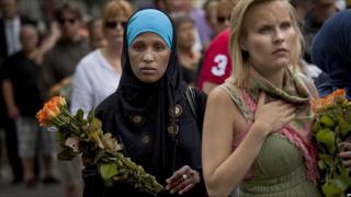 Two women carry flowers as they arrive for a memorial service at Oslo Cathedral