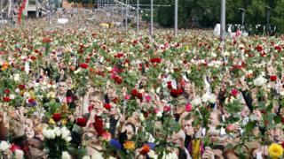 Thousands of people on the streets of Oslo, raising flowers in memory of those who were killed
