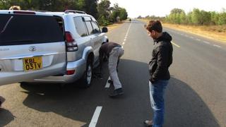 Ricky watches the car tyre being changed on the way to Dadaab