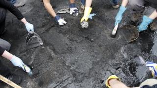 Volunteers clearing up the remains from a burnt out vehicle in Hackney, north London
