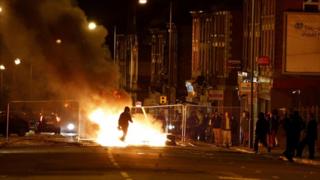 A rioter walks through a burning barricade in Liverpool, where about 200 rioters in the Toxteth area chucked missiles and caused damage