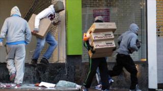 Looters carry boxes out of a home cinema shop in central Birmingham