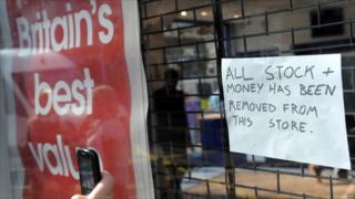 A woman takes a photograph of a sign in a mobile phone shop in Clapham Junction, south London