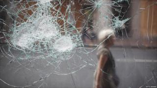 A woman walks past a broken cafe window in Clapham Junction