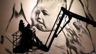 Two graffiti artists look at their painting of a baby in Bristol.