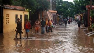People walking through flood water on the streets of San Cristobal in Hispaniola.