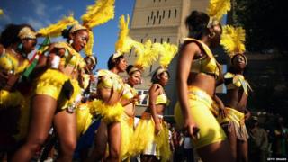 Women parading in yellow carnival costumes with yellow feathered headdress