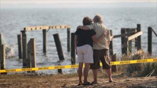 Billy Stinson (right) is comforted by Gayle Felton as he looks at the remains of his cottage in Nags Head, North Carolina, on 28 August 2011