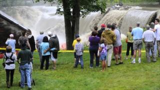 Residents in Windsor, New Hampshire, watch as water rushes over the Ascutney Mill Dam on Kennedy's Pond, on 28 August 2011