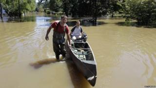 Gino Borova, left, gives a canoe ride to his neighbour, Tom Soboleski, as they made their way through floodwaters after looking at their houses in New Jersey, where the Ramapo River flooded in the aftermath of Hurricane Irene.