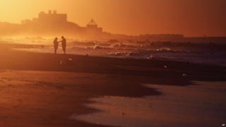 People stand on the beach at Coney Island in Brooklyn New York at sunrise on August 29 after Tropical Storm Irene hit.