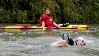 A kayaker keeps watch as David Walliams swims down the River Thames