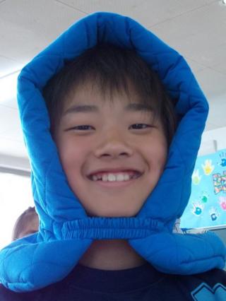 A school child wearing a blue cushioned hood.