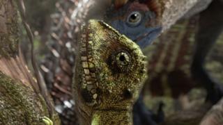A lizard looking at a dinosaur