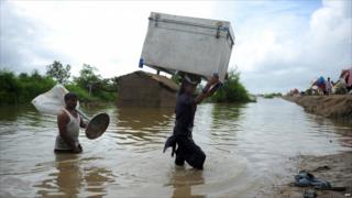 Villagers carry their belongings through flood water in south Pakistan