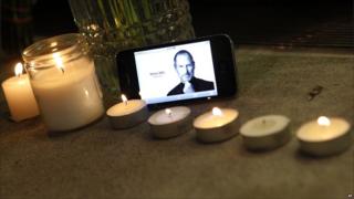 An iPhone displays an image of Steve Jobs at a makeshift memorial outside an Apple store in New York