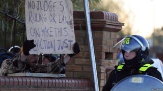 Resident holding protest sign up to a police officer