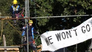 Enforcement officers on scaffolding removing sign