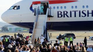 Queen and Prince Philip waving on steps of plane