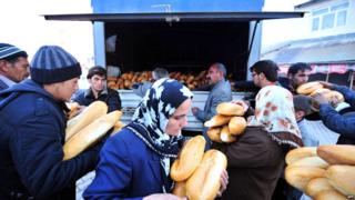 Local people collecting breadsticks from a van